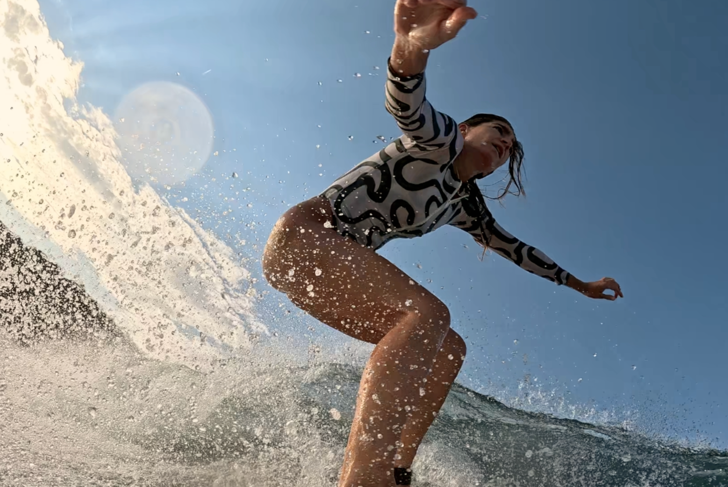 Person surfing on a wave with a clear blue sky