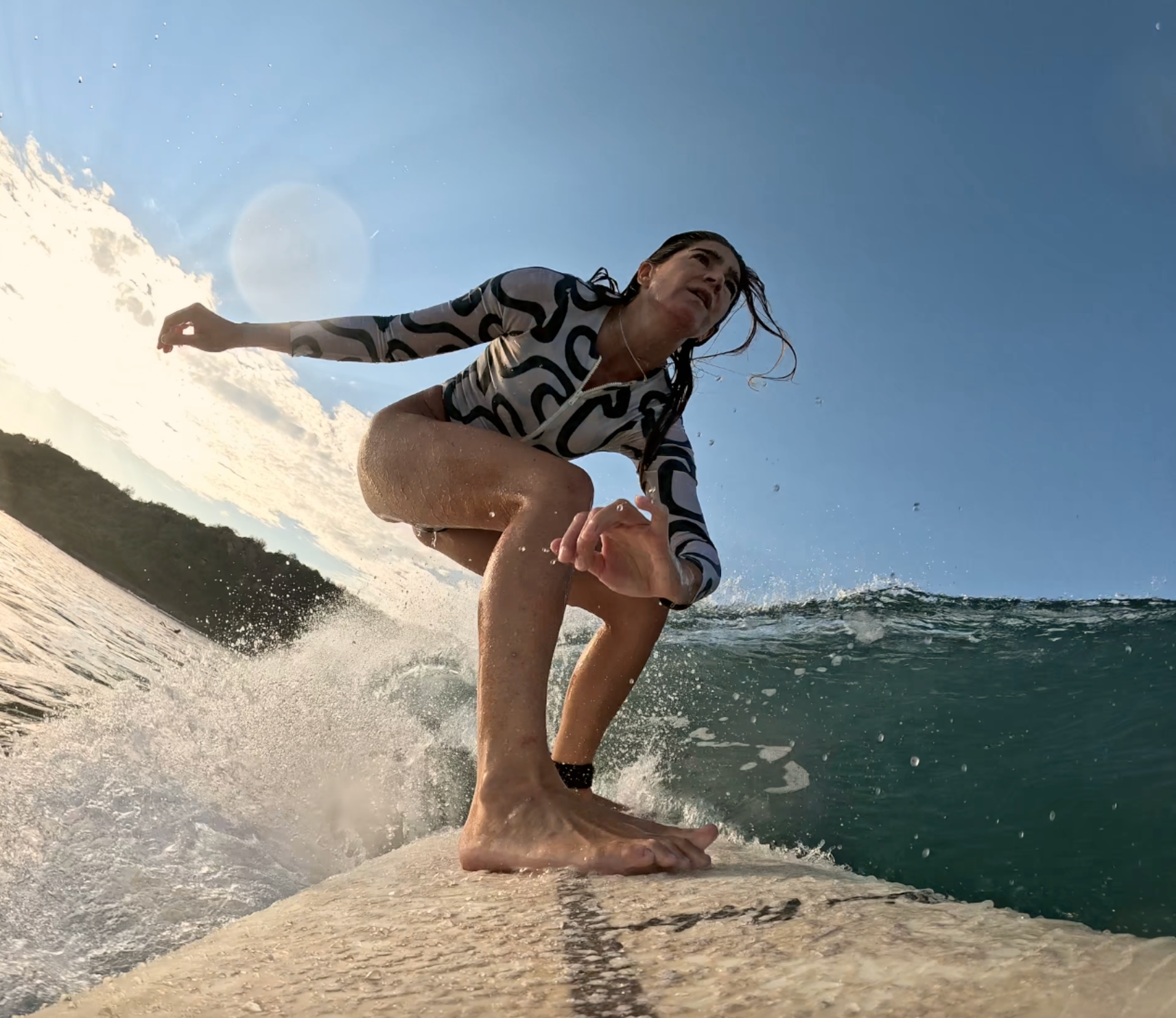 Woman surfing on a wave with a clear blue sky